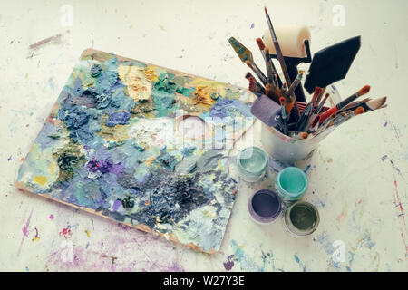 Artistic equipment: painter palette, paint brushes, paints and palette knifes. Top view. Stock Photo
