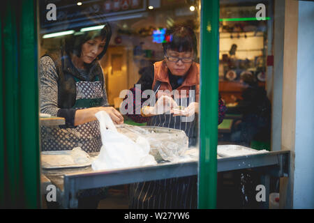 London, UK - April, 2019. Female cooks preparing dumplings in a restaurant in China Town in Soho. Stock Photo