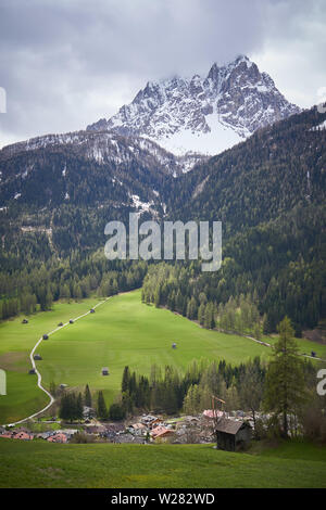 View of a valley in the Alps in the region Trentino with the typical wooden barns (Tabia in Italian) and the Dolomites on the background. Stock Photo