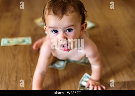 Baby happy to earn his own money, dollar bills that a father gives his son as a family to save them. Stock Photo