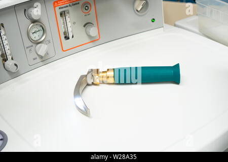Laryngoscope with a Macintosh blade in a working position, light on, laid out on top of an anesthesia machine Stock Photo