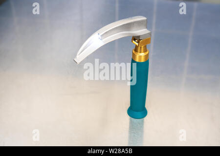 Laryngoscope (a tool used for intubation) with a Macintosh blade in a working position, light on, laid out on top of a Mayo stand Stock Photo
