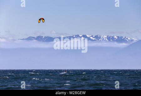 Person Windsurfing Juan De Fuca Strait Water Waves. Windy Day James Bay Victoria BC Canada Distant Olympic Peninsula Washington Mountain Peaks Skyline Stock Photo