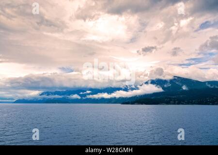 Howe Sound Dramatic Sunset Sky Landscape and Low Clouds over Coast Mountains of British Columbia near Vancouver, Canada Pacific Northwest Stock Photo