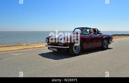 Classic Purple Triumph TR6 Sports Car being driven along Seafront  Promenade. Stock Photo