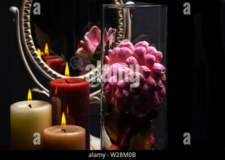 Vintage Oval Desk Mirror with white frame, potpourri, and candles reflecting in mirror on black background Stock Photo