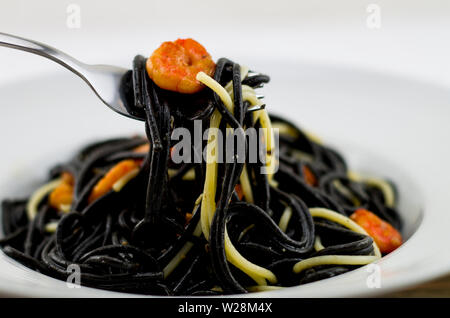 Italian black spaghetti with prawns and dried tomatoes. Stock Photo