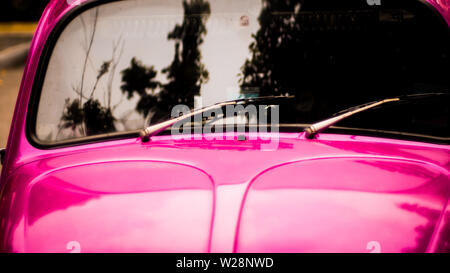 Close up of rear windshield wiper arm and blade on sun bleached pink vintage motor vehicle Stock Photo