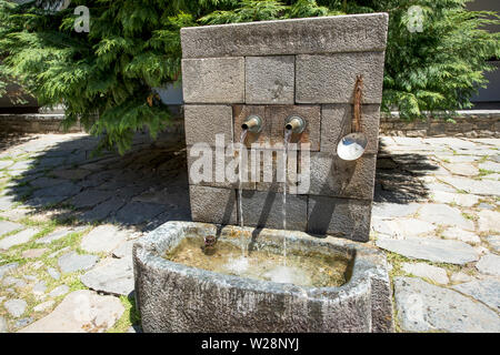 Stone fountain with two iron spouts. The metal spouts of the old old stone fountain Stock Photo