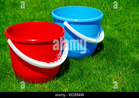 Colored plastic garden buckets on background of green grass Stock Photo