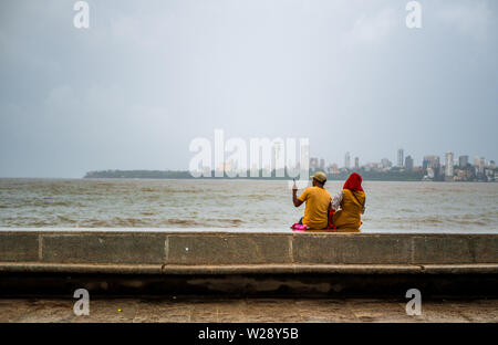 Mumbai, India - June 30, 2019 : Unidentified couple taking photos / selfie with Mobile at Marine Drive promenade Stock Photo