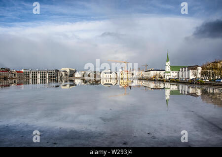 Reykjavik, Iceland, February 23, 2019: the historic town center on the north bank of Lake Tjornin between town hall and Frikirkja church reflects in t Stock Photo