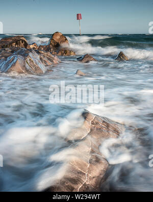 waves crashing over rocks on the coast Stock Photo