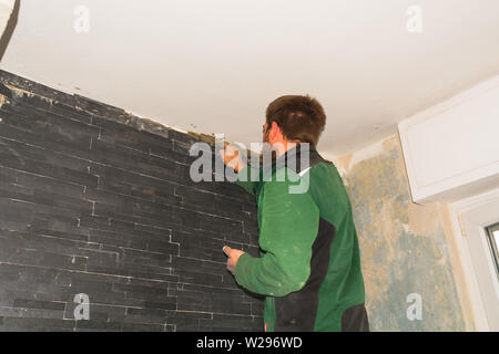 Ceramic tiles. Tilers of ceramic tiles glued to the wall Stock Photo