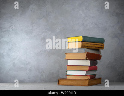 Stack of books on the table against the wall Stock Photo