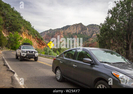 Sedona, Arizona, USA - May 5, 2019: Cars move to avoid potholes and pedestrians on the narrow winding mountain roads of Sedona, Arizona, with a watch Stock Photo