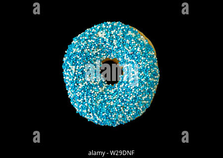 Blue donut. One donut with blue and white decoration isolated on black color background. Top view Stock Photo