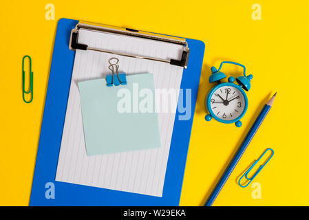 Clipboard sheet note binder pencil clips alarm clock colored background Stock Photo