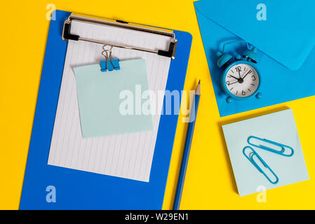 Clipboard sheet note binder pencil clips clock envelop colored background Stock Photo