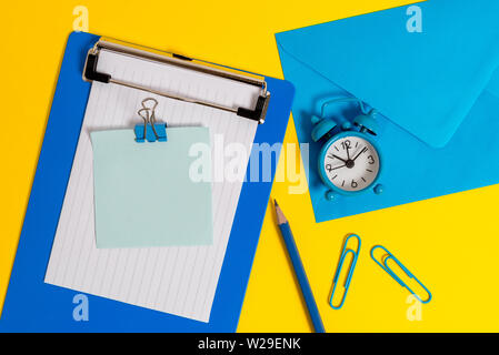 Clipboard sheet note binder pencil clips clock envelop colored background Stock Photo