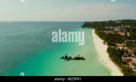 White sand beach and Willy's rock with tourists and hotels and sailing boat on Boracay Island. Aerial drone: Tropical white beach with sailing boat. Summer and travel vacation concept. Stock Photo