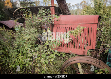Abandoned Antique Tractor In Field. Farm field with rusted vintage tractor in an overgrown field. Stock Photo