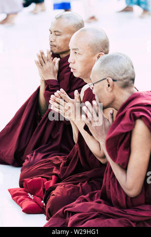 Yangon, Myanmar - March 2019: Buddhist monks pray in Shwedagon pagoda temple complex. Stock Photo