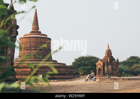 Man riding electric scooter towards temples and pagodas of ancient Bagan in Myanmar. Stock Photo