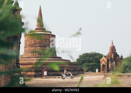 Man riding electric scooter towards temples and pagodas of ancient Bagan in Myanmar. Stock Photo