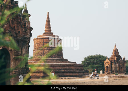 Man riding electric scooter towards temples and pagodas of ancient Bagan in Myanmar. Stock Photo