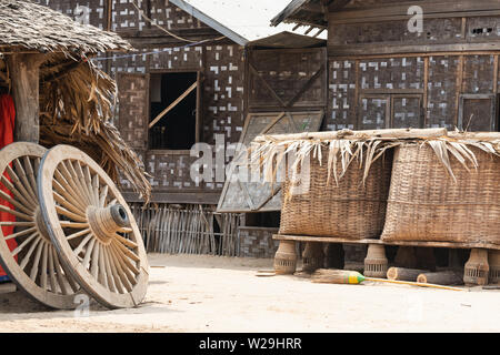 Rustic village farm backyard with bamboo hut, baskets and two wooden wheels in Bagan, Myanmar Stock Photo