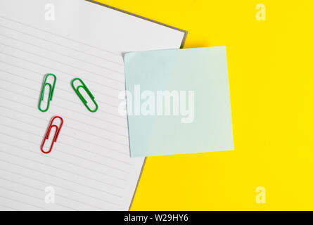 Empty blue paper with copy space paper clips and pencils on the yellow table. Stock Photo