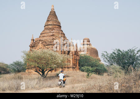 Man riding electric scooter towards temples and pagodas of ancient Bagan in Myanmar. Stock Photo