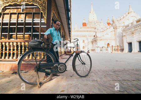 Bagan, Myanmar - March 2019: Burmese man parking bicycle in the backyard of Ananda temple at sunset