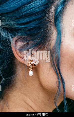 Closeup of a female ear with an earring. A girl with blue hair. Stock Photo