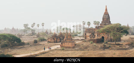 Bagan, Myanmar - March 2019: people walking through ancient temples and pagodas at sunset.