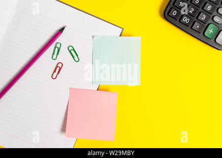Empty blue paper with copy space paper clips and pencils on the yellow table. Stock Photo