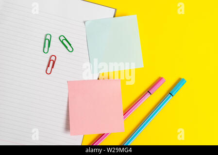 Empty blue paper with copy space paper clips and pencils on the yellow table. Stock Photo