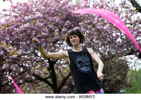 A young woman enjoying herself poi spinning in Saint Stephen's Green, Dublin as Dublin enjoys beautiful weather Stock Photo