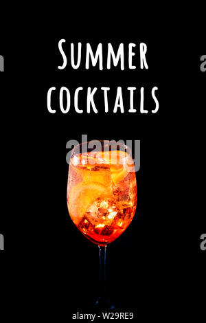 Stylish alcoholic aperol spritz trendy cocktail with orange slice on black background. Vertical photo. Summer cocktails wording Stock Photo