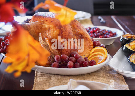 Family dining room table set with raost stuffed turkey for Thanksgiving Day. Selective focus on turkey with blurred background.. Stock Photo