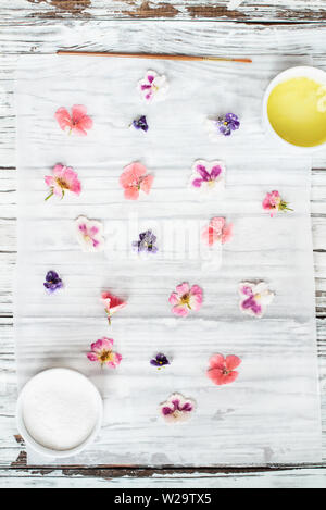 Ingredients for making homemade sugared or crystallized edible flowers on a white wooden rustic table. Image shot for above. Stock Photo