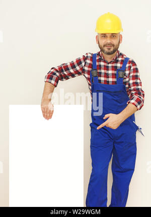 Worker with helmet in protective equipment holding white board for text copy space Stock Photo