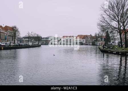 Haarlem, Netherlands - February 5, 2019: Splendind gray cityscape of old city. Black water of Spaarne river reflecting shadows of the trees. Stock Photo