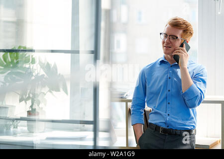 Young restful office worker consulting someone on smartphone Stock Photo