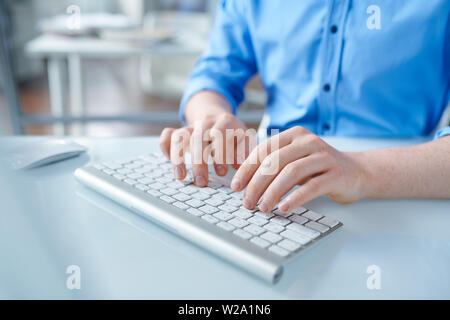 Creative designer in blue shirt touching buttons of computer keypad Stock Photo