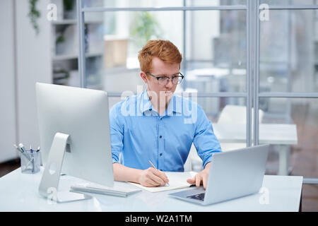 Young programmer looking through software on laptop display Stock Photo