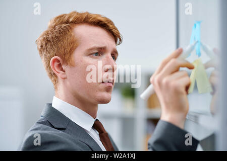 Young confident business or financial expert pointing at note on board Stock Photo