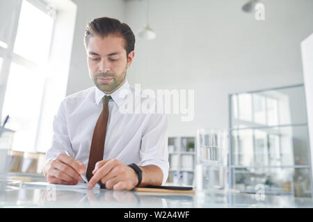 Young confident lawyer making working notes on paper Stock Photo