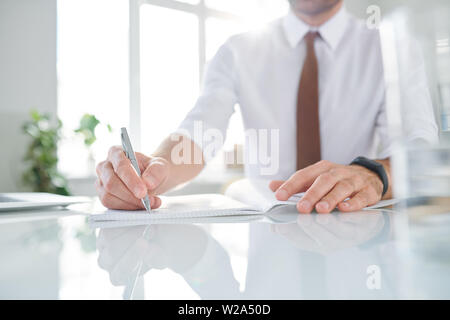 Elegant contemporary businessman making working notes in copybook Stock Photo